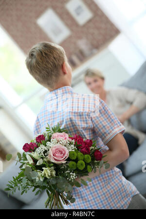 Sohn verstecken Blumenstrauß Mama am Muttertag überraschen Stockfoto