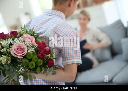 Sohn verstecken Blumenstrauß Mama am Muttertag überraschen Stockfoto