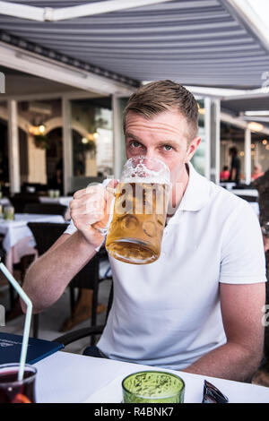 Junger Mann mit einem großen Glas kühles Bier. Menorca Stockfoto