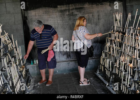 Menschen Beleuchtung Votiv Kerzen in Virgen del Rocío El Rocio, Spanien. Stockfoto