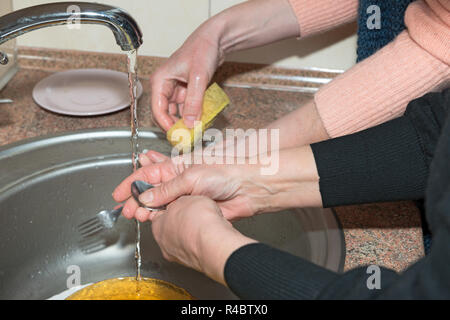 Close-up waschen Geschirr in vier Frauen Hände in der Küche aus Edelstahl Waschbecken. Stockfoto