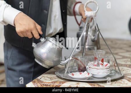 Die Hände des Menschen (Tee) mit Metall türkische Teekanne Tee in Glas Tassen in einem Kaffeehaus in der Türkei gießen Stockfoto