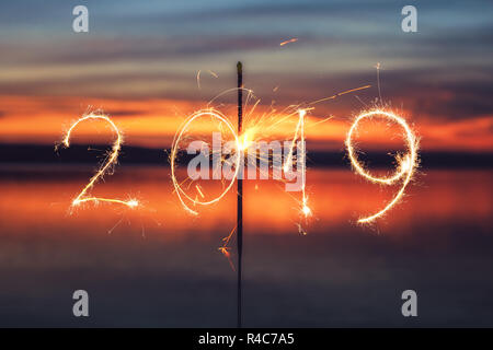 2019 mit Schein Feuerwerk auf dem Sunset Hintergrund geschrieben, glückliches neues Jahr 2019. Stockfoto