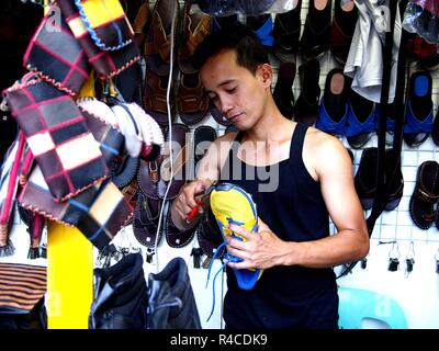 ANTIPOLO CITY, Philippinen - November 24, 2018: Ein Arbeiter von einem Schuh Reparatur shop behebt ein paar Schuhe. Stockfoto