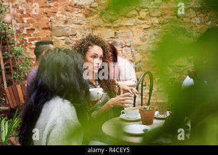 Junge Frau mit Freunden chatten in einem angesagten Café Hof Stockfoto