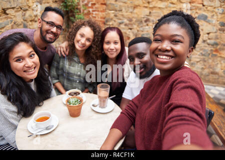 Diverse junge Freunde selfies, die zusammen in einem Cafe im Innenhof Stockfoto