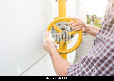 Power Station Arbeiter. Mann Ingenieur in Helm und Shirt twist Gasleitung Ventil Stockfoto
