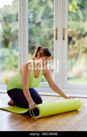 Frau, die eine Yogamatte ausrollt Stockfoto