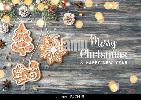 Text frohe Weihnachten und ein glückliches Neues Jahr, Gingerbread Cookies & Weihnachtsschmuck im Urlaub Grußkarte. Glänzende Girlande Lichter. Stockfoto