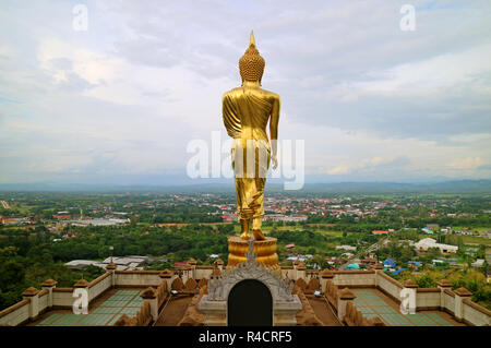 Atemberaubende gold Buddha Bild in der Haltung gegenüber der Stadt von Nan, Wat Phra That Khao Noi Tempel, historischer Ort im Norden von Thailand farbige Stockfoto