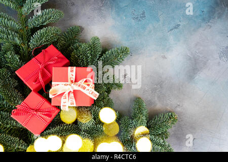 Weihnachten Geschenk, das Konzept - drei Weihnachtsgeschenke in roten Kästen auf immergrüne Tannenbaum Äste mit Kopie Raum Stockfoto
