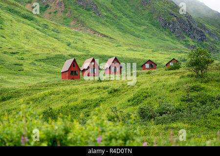 Abgebrochene rot Kabinen sitzen im grünen üppigen Berge von Alaska Hatcher Pass in der Nähe von Independence Mine. Stockfoto