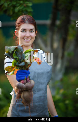 Das Bild der jungen Frau mit rote Beete im Garten, verschwommenen Hintergrund Stockfoto