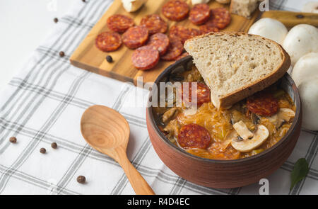 Slowakische Weihnachten nationalen Kohlsuppe in Keramik Schüssel mit Wurst auf der Tischdecke Hintergrund. Stockfoto