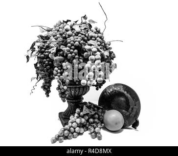 Hoher Kontrast schwarz und weiß immer noch das Leben der Trauben in eine Vase vor einer Orange und einer Glasplatte. Stockfoto