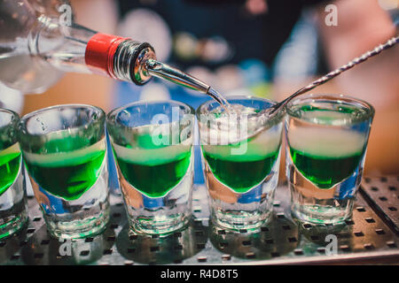 Grüne Flüssigkeit in Shot Gläser stehen auf dem Zähler. Barkeeper Vorbereitung Schüsse Stockfoto