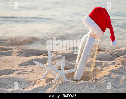 Santa Hut auf Nachricht in einer Flasche mit weißer Seestern in Strand sand Stockfoto