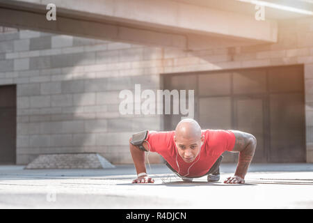 Starker junger Mann Liegestütze machen während des Trainings Stockfoto