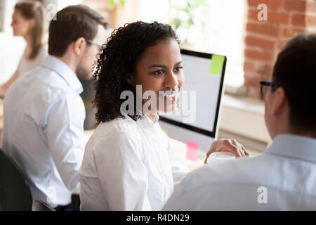 Lächelnde junge afrikanische amerikanische Frau im Gespräch mit Kollegen Stockfoto