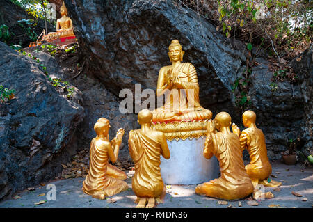 Goldenen Buddhas mit Jüngern mit Händen in der Lehre gehalten ( vitarka, Lehre mundra) im felsigen Einstellung auf Mount Phousi, Luang Prabang, Laos Stockfoto