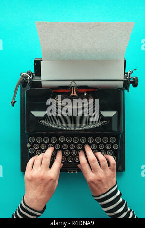Frau Eingabe vintage Schreibmaschine, Blick von oben auf die Hände auf blauem Hintergrund Stockfoto