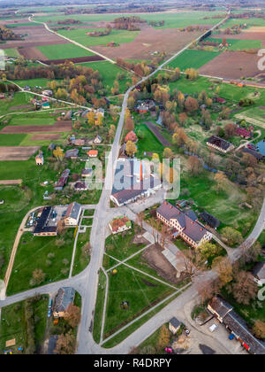 Antenne Drone Foto von einem Dorf mit Wiesen in schöner Frühling Farben in Abend Umgeben mit Sonnenuntergang über es Stockfoto