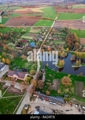 Antenne Drone Foto von einem Dorf mit Wiesen in schöner Frühling Farben in Abend Umgeben mit Sonnenuntergang über es Stockfoto