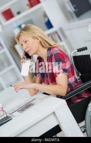 behinderte Frau im Rollstuhl, die professionell tätigen Stockfoto