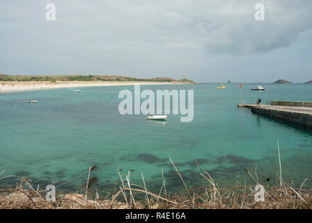 Blick auf atemberaubende Par Strand, St Martin's, Scilly, mit unberührten weißen Sandstrand, blaues Meer und kleine Boote und höhere Town Quay Jetty. Stockfoto