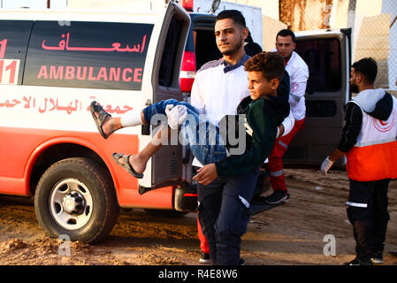 Gaza, Palästina. 26. Nov 2018. Ein medic gesehen mit einem verletzten Kind während der Auseinandersetzungen zwischen Palästinensern und der israelischen Besatzungstruppen im nördlichen Gazastreifen in der Nähe der Basis der Zakim aus Protest gegen die Anerkennung von Jerusalem als Hauptstadt von Israel durch US-Präsident Trump und weigerte sich, den Gazastreifen zu blockieren. Credit: SOPA Images Limited/Alamy leben Nachrichten Stockfoto