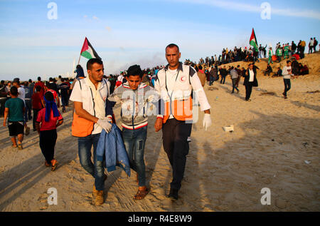 Gaza, Palästina. 26. Nov 2018. Palästinensische Mediziner mit einem verletzten jungen Mann während der Auseinandersetzungen zwischen Palästinensern und der israelischen Besatzungstruppen im nördlichen Gazastreifen in der Nähe der Basis der Zakim aus Protest gegen die Anerkennung von Jerusalem als Hauptstadt von Israel durch US-Präsident Trump gesehen und abgelehnt, den Gazastreifen zu blockieren. Credit: SOPA Images Limited/Alamy leben Nachrichten Stockfoto