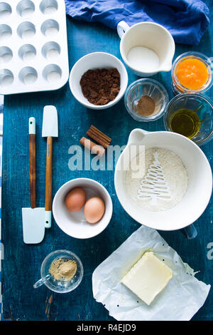 Zutaten einige muffin Kürbis für Halloween vorbereitet sind auf einer Blu rustikalen Board angezeigt, flach Draufsicht, natürliche Beleuchtung. Stockfoto