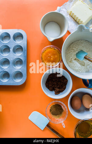 Zutaten einige muffin Kürbis für Halloween vorbereitet sind auf einer Blu rustikalen Board angezeigt, flach Draufsicht, natürliche Beleuchtung. Stockfoto