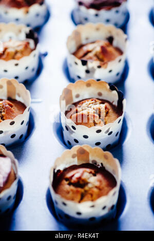 In der Nähe der frisch gebackenen pumpkin Muffin gesäumt auf einem Backblech aus Aluminium für Halloween auf Blu rustikalen Board angezeigt, flach Draufsicht, nat Stockfoto