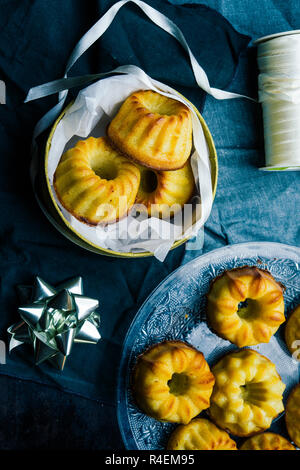 Weihnachten mini bundt Cake und Dekoration auf einem Brett mit Weihnachten Dekoration, eine goldene Paket und Schere, Ansicht von oben, flach copyspace legen. Stockfoto