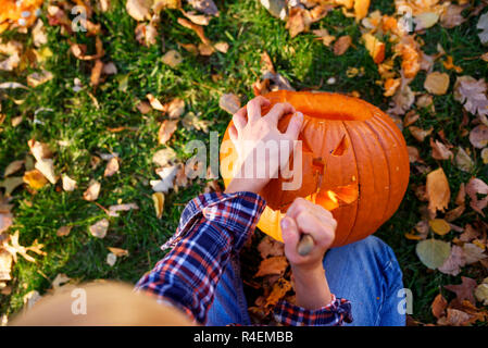 Ansicht eines Jungen Schnitzen eines Halloween Kürbis im Garten, United States Stockfoto