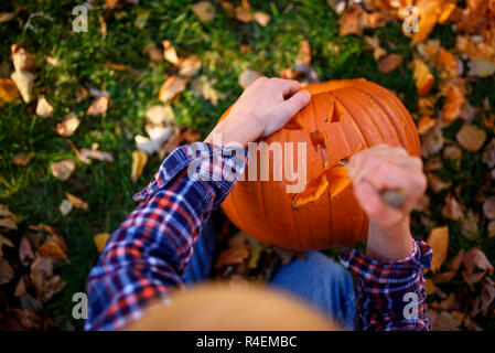 Ansicht eines Jungen Schnitzen eines Halloween Kürbis im Garten, United States Stockfoto