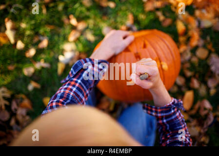 Junge Schnitzen eines Halloween Kürbis im Garten, United States Stockfoto