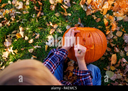 Junge Schnitzen eines Halloween Kürbis im Garten, United States Stockfoto