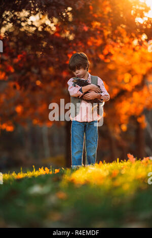 Junge draußen Kuscheln ein Huhn, United States Stockfoto