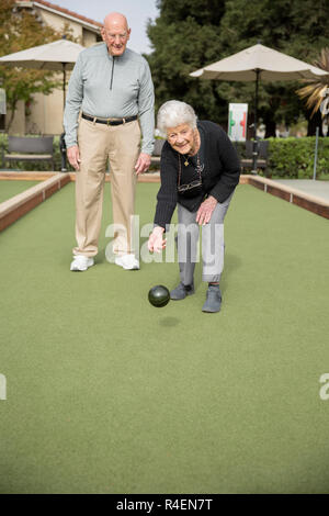 Ältere Frau, Bowling, Mann im Hintergrund Stockfoto