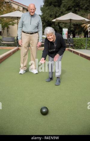 Ältere Frau, Bowling, Mann im Hintergrund. Stockfoto