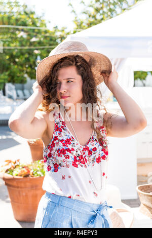 Junge Frau Einkaufen für Stroh Beach Hut auf im freien Markt shop shop in Florida, Europäischen, Griechenland, Italien, mediterrane Stadt, Dorf in Co Stockfoto