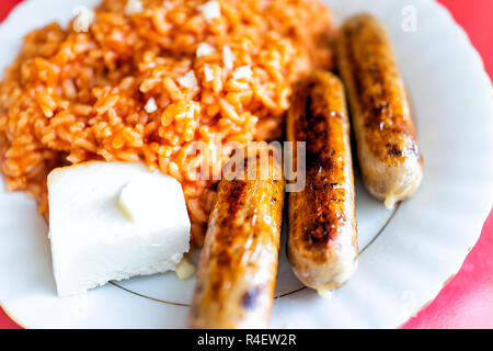 Nahaufnahme des großen Mittagessen Abendessen Platte mit gebratenen drei Würstchen, Tomate, roter Reis, Käse Cube, orange Farbe fettig Essen Stockfoto