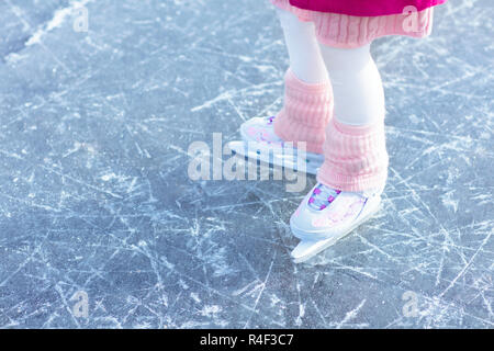 Kind Schlittschuhlaufen auf Natureis auf sonnigen Wintertag. Kinder mit Schlittschuhen. Kleines Mädchen Schlittschuhlaufen auf zugefrorenen See in Snowy Park. Schnee und Winter Spaß. Gesunde heraus Stockfoto