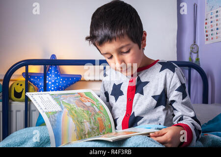 UK, Junge,7 Jahre alt liest im Bett Stockfoto