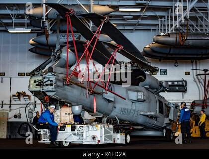 Pazifik (1. Mai 2017) der Luftfahrt Bootsmann Mate (Handling) Airman Matthew Kuhns verwendet einen Traktor für den Transport von einem MH-60R Sea Hawk Hubschrauber zum 'Battlecats' der Hubschrauber Maritime Strike Squadron (HMS) 73 zugeordnet im Hangar Bucht der Flugzeugträger USS Theodore Roosevelt (CVN 71). Das Schiff ist unterwegs die Durchführung einer Gruppe Sail Training Unit Übung mit dem es Carrier strike Group. Stockfoto