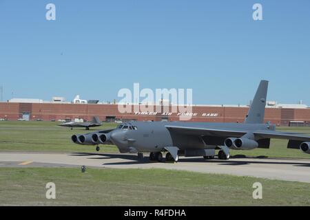 Zwei wesentliche Verteidigungskapazitäten zusammengefasst als Boeing B-52 H, 60-0005, vor dem Oklahoma City Air Logistics wirft komplexe während einer F-22A Raptor der 325 Fighter Wing, Tyndall Air Force Base in Florida, die Rollen der Start- und Landebahn am 1. Mai 2017, Tinker Air Force Base, Oklahoma. OC-ALC ist verantwortlich für das Depot Instandhaltung der B-52-Flotte sowie die Überholung der Pratt & Whitney F119-Motoren in der F-22 A eingesetzt. Stockfoto