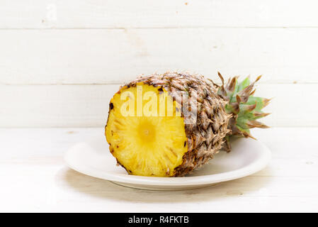 Die Hälfte bio Ananas auf einer Platte, weiß Holz- Hintergrund mit Kopie Raum gemalt, ausgewählte konzentrieren, enge Tiefenschärfe Stockfoto