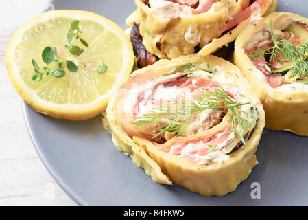 Pfannkuchen roll Scheiben mit Lachs, Frischkäse und Kräutern auf einem blauen Platte, ausgewählte konzentrieren, enge Tiefenschärfe Stockfoto